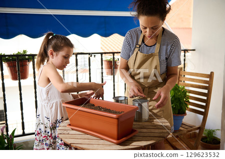 Mother and Daughter Gardening Together on a Sunny Balcony Mother and Daughter Gardening Together on a Sunny Balcony 129623532