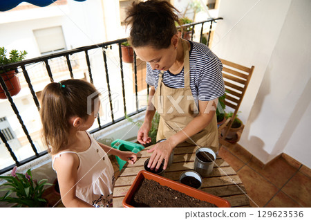Mother and Daughter Gardening Together on Balcony in Sunny Settings Mother and Daughter Gardening Together on Balcony in Sunny Settings 129623536