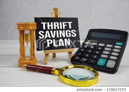 TSP Thrift Savings Plan text with magnifying glass and calculator on wooden background TSP Thrift Savings Plan text with magnifying glass and calculator on wooden background 129623555