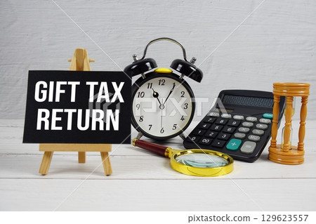 Gift Tax Return text with magnifying glass and calculator on wooden background Gift Tax Return text with magnifying glass and calculator on wooden background 129623557