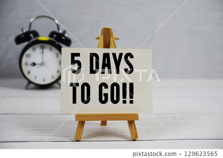 5 Days To Go! text with easel and alarm clock on wooden background 5 Days To Go! text with easel and alarm clock on wooden background 129623565