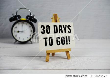 30 Days To Go! text with easel and alarm clock on wooden background 30 Days To Go! text with easel and alarm clock on wooden background 129623576