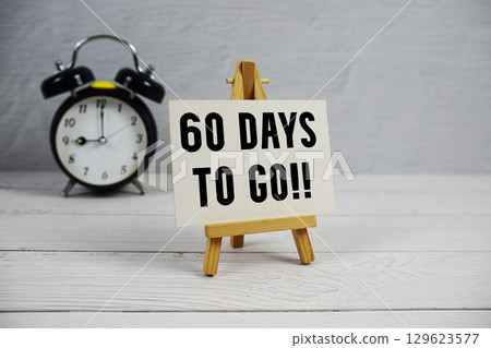 60 Days To Go! text with easel and alarm clock on wooden background 60 Days To Go! text with easel and alarm clock on wooden background 129623577