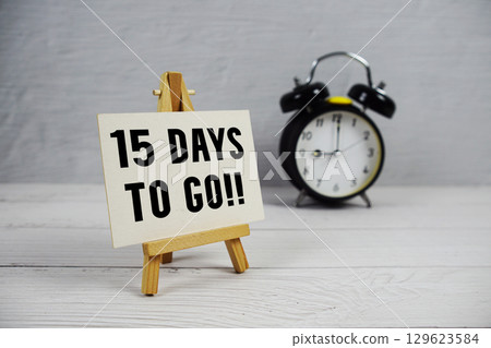 15 Days To Go! text with easel and alarm clock on wooden background 15 Days To Go! text with easel and alarm clock on wooden background 129623584