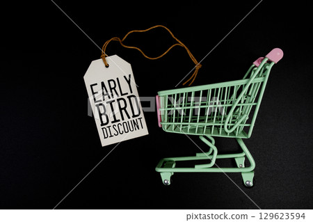 Early Bird Discount text on price tag and trolley shopping cart on black background 129623594