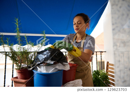 Woman Gardening on Balcony Focuses on Sustainable Waste Practices 129623703