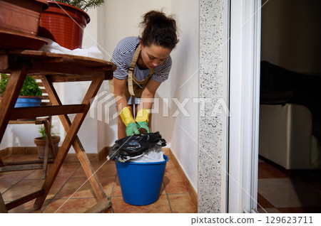 Woman Cleaning Patio with Gloves Focused on Home Maintenance Task 129623711