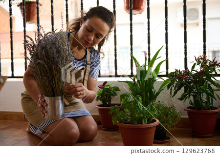Young Woman Gardening on a Patio Surrounded by Houseplants and Sunshine 129623768