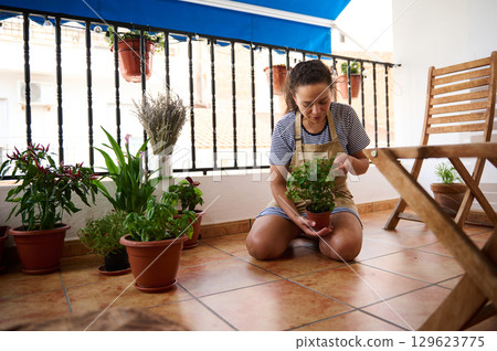 Woman Caring for Plants on a Sunny Balcony with Relaxing Atmosphere 129623775