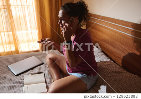 Worried Woman Talking on the Phone in a Sunlit Room 129623898
