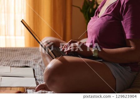 Woman Working Remotely From Bed Using Laptop in Cozy Environment 129623904