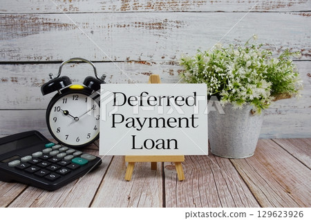 Deferred Payment Loan text with alarm clock and calculator on wooden background 129623926