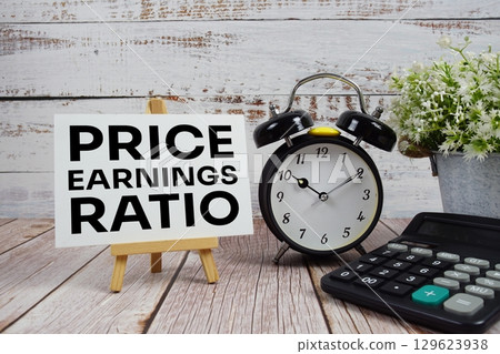 Price Earnings Ratio text with alarm clock and calculator on wooden background Price Earnings Ratio text with alarm clock and calculator on wooden background 129623938