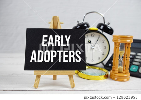 Early Adopters text with magnifying glass and calculator on wooden background 129623953