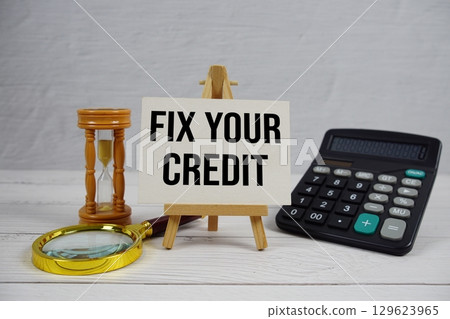 Fix Your Credit text with magnifying glass and calculator on wooden background 129623965