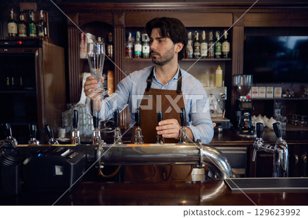 Brewer man brewer is carefully pouring beer into a glass 129623992
