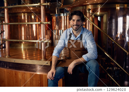 A man wearing an apron is sitting on a rustic wooden floor in a bar 129624028