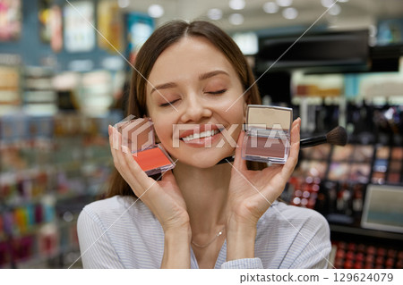 A happy woman holding two blush compacts, showcasing her love 129624079