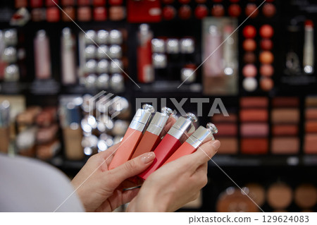 A woman is carefully holding a beautiful row of colorful lipsticks in her hands 129624083