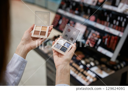 A woman is confidently holding two beautiful eyeshadow palettes in her hands A woman is confidently holding two beautiful eyeshadow palettes in her hands 129624091