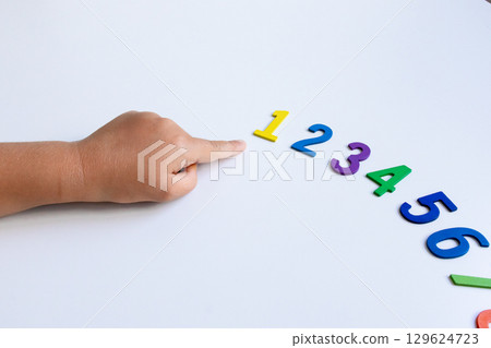 Child learning numbers with colorful foam digits on white background 129624723