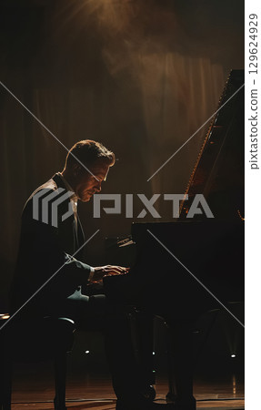 professinal pianist playing on piano at dark stage, man play at performance on grand piano instrument, back light and illumination professinal pianist playing on piano at dark stage, man play at performance on grand piano instrument, back light and illumination 129624929