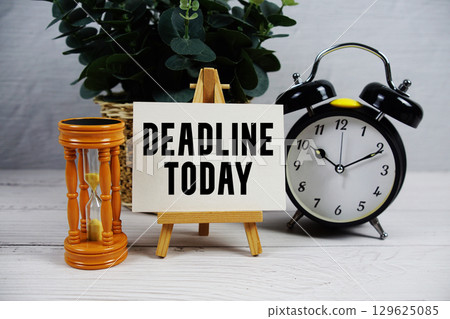 Deadline Today text with hourglass and alarm clock on wooden background 129625085