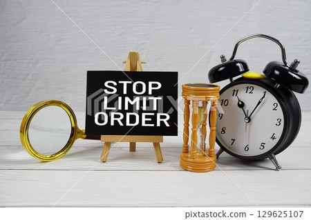 Stop Limit Order text with magnifying glass, hourglass and alarm clock on wooden background 129625107