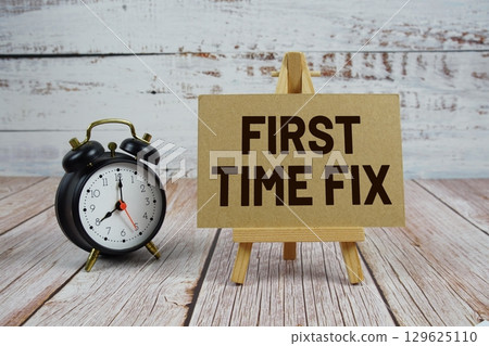 First Time Fix text with easel and alarm clock on wooden background First Time Fix text with easel and alarm clock on wooden background 129625110
