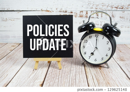 Policies Update text with easel and alarm clock on wooden background 129625148