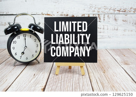 Limited Liability Company text with easel and alarm clock on wooden background 129625150