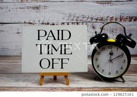 Paid Time Off text with easel and alarm clock on wooden background 129625161