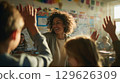 Smiling teacher giving high five to her cheerful students in classroom before math lesson 129626309