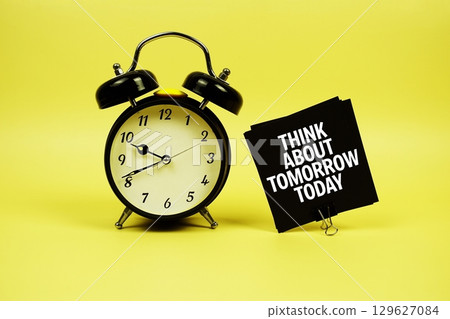 Think About Tomorrow Today text message on paper card with alarm clock on yellow background Think About Tomorrow Today text message on paper card with alarm clock on yellow background 129627084
