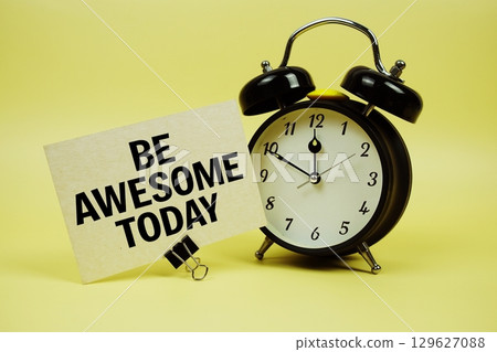 Be Awesome Today text message on paper card with alarm clock on yellow background 129627088