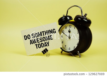 Do Something Awesome Today text message on paper card with alarm clock on yellow background 129627089