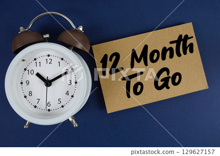 12 Month To Go text written on paper with alarm clock on blue background 12 Month To Go text written on paper with alarm clock on blue background 129627157