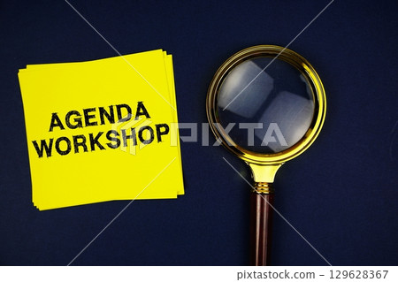 Agenda Workshop text on sticky note with magnifying glass on navy blue background 129628367