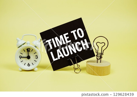 Time To Launch text message on paper card with alarm clock on yellow background Time To Launch text message on paper card with alarm clock on yellow background 129628439