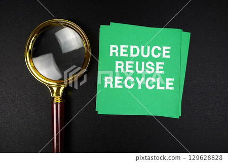 Reduce Reuse Recycle text on sticky note with magnifying glass on black background 129628828
