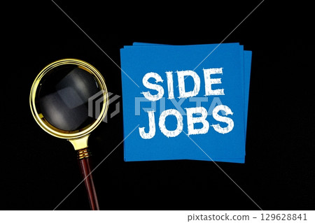 Side Jobs text on sticky note with magnifying glass on black background 129628841