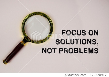 Focus On Solutions, Not Problems text with magnifying glass on pink background 129628917