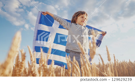 Patriot Boy Standing Wheat Field Holding Greek Hellas Flag in the Wind, Homeland 129629239