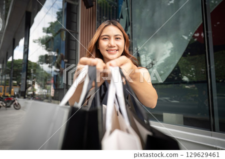 Black Friday shopping excitement. Happy woman holding shopping bags outdoors. 129629461