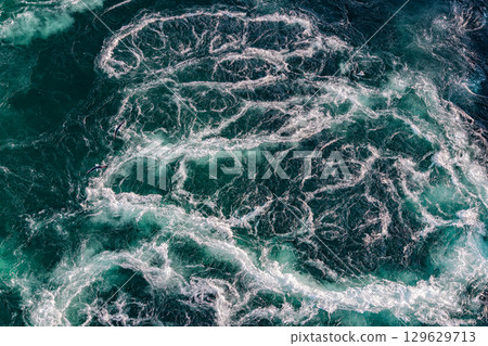 Blue waves of water of the river and the sea meet each other during high tide and low tide. Blue waves of water of the river and the sea meet each other during high tide and low tide. 129629713