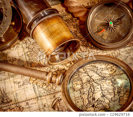 Vintage style travel and adventure. Vintage old compass and other vintage items on the table. Vintage style travel and adventure. Vintage old compass and other vintage items on the table. 129629716