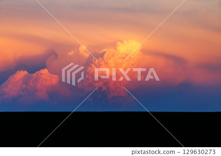 An incredible colorful sunset with cumulonimbus clouds illuminated by the sun. 129630273