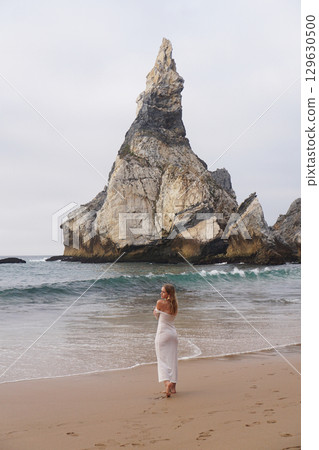 In Solitude by the Ocean A Woman Walking Alone Peacefully on the Beautiful Scenic Beachside 129630500