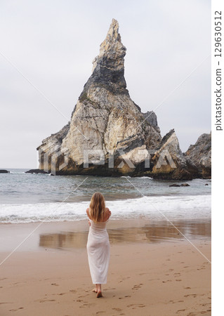 In Solitude by the Ocean A Woman Walking Alone Peacefully on the Beautiful Scenic Beachside In Solitude by the Ocean A Woman Walking Alone Peacefully on the Beautiful Scenic Beachside 129630512