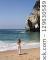 In Solitude by the Ocean A Woman Walking Alone Peacefully on the Beautiful Scenic Beachside 129630589